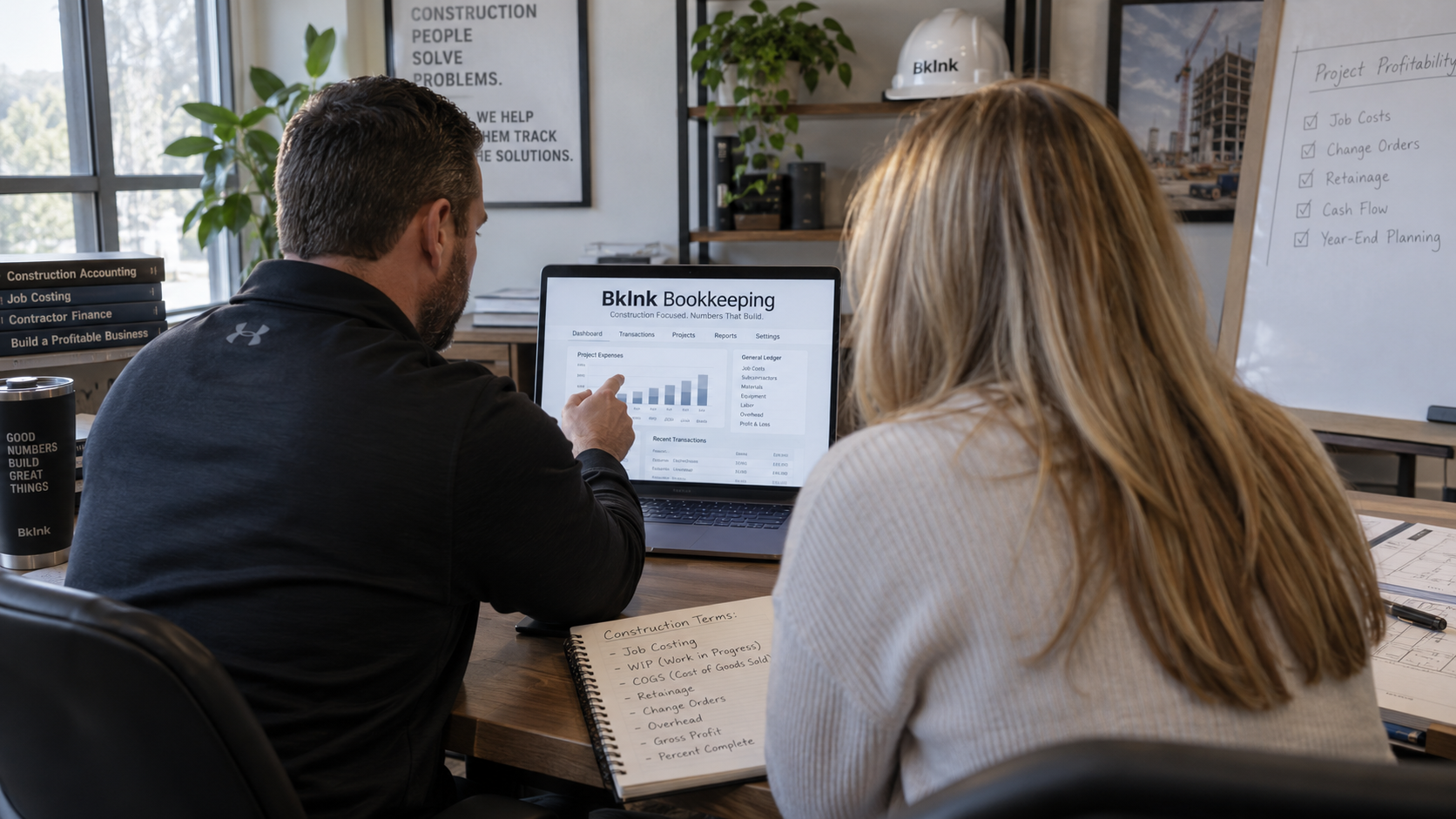 Construction company owner and BKInk bookkeeper reviewing project expenses and job costing in QuickBooks Online, with a project profitability checklist on the whiteboard